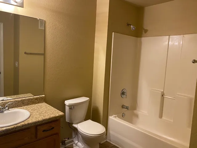 a bathroom with a granite countertop toilet a sink and a bathtub