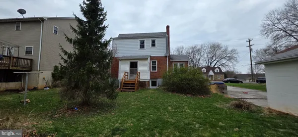 a backyard of a house with plants and large tree