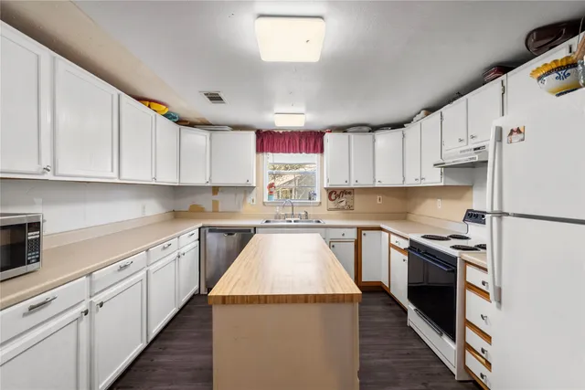 a kitchen with kitchen island granite countertop a sink a counter top space stainless steel appliances and cabinets