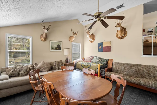 a living room with couches a fireplace and a dining table with wooden floor