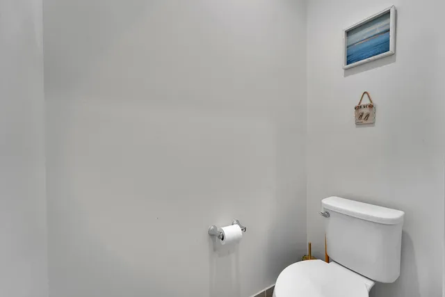 a white toilet sitting next to a white wall