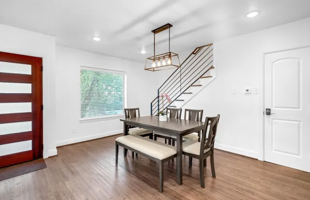 a dining room with wooden floor a chandelier a wooden table and chairs
