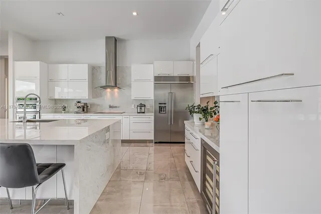 a large white kitchen with a large window and stainless steel appliances