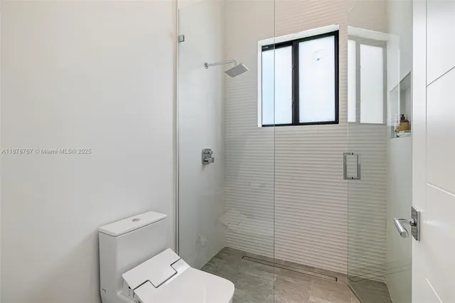 a bedroom with a bed a large mirror and window