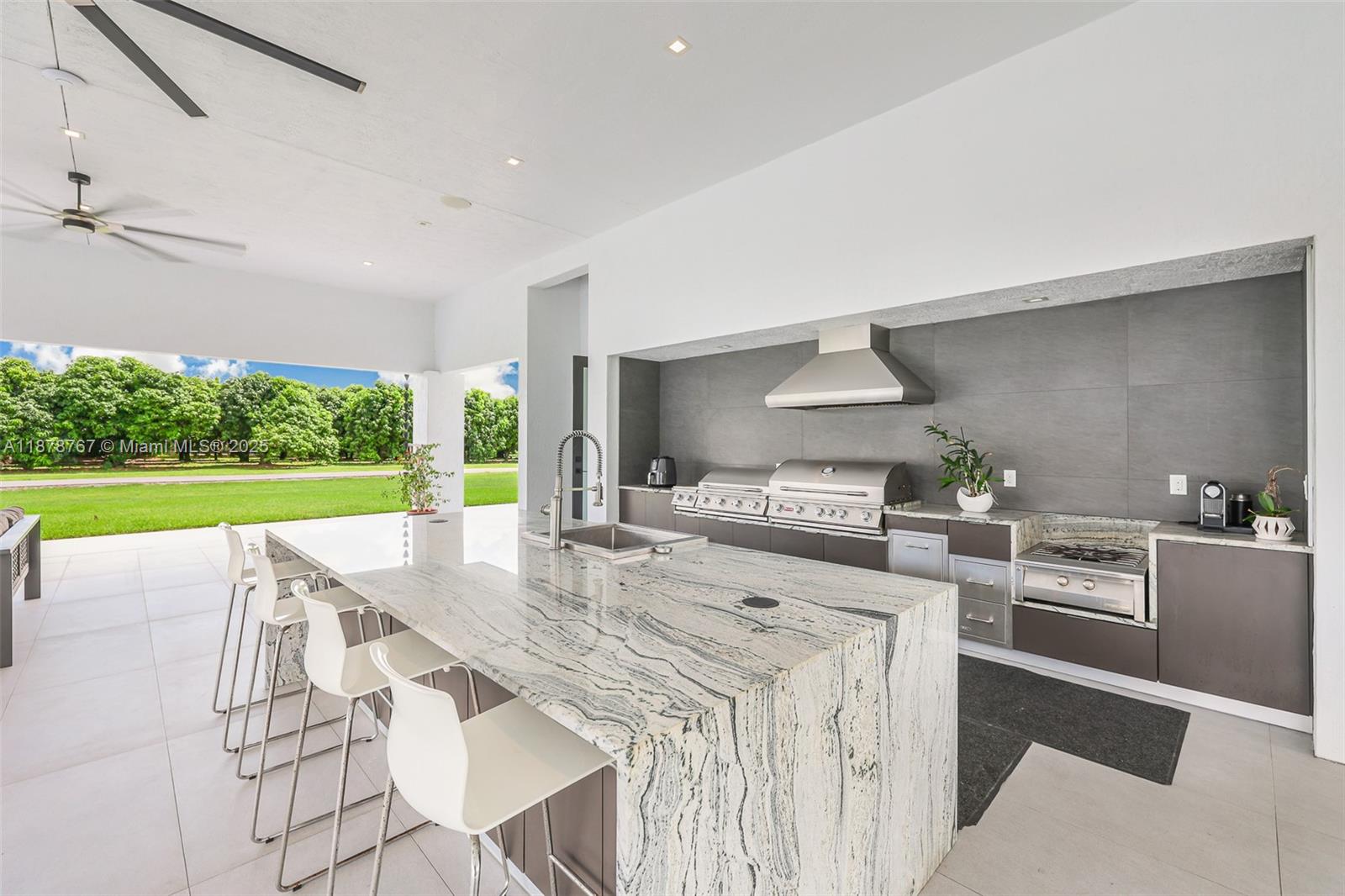 17950 Southwest 192nd Street Miami, FL 33187 - Photo 48 of 53 a kitchen with stainless steel appliances kitchen island granite countertop a table and chairs in it