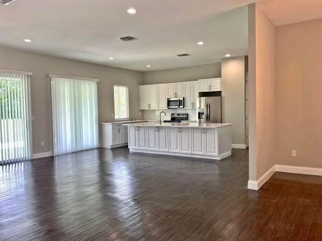 a view of a kitchen with kitchen island wooden floors and stainless steel appliances