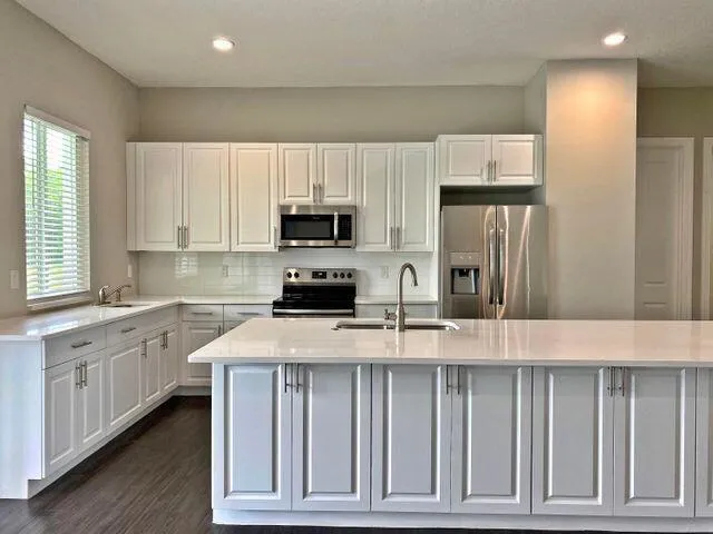a kitchen with kitchen island granite countertop a stove a sink and a refrigerator with wooden floor