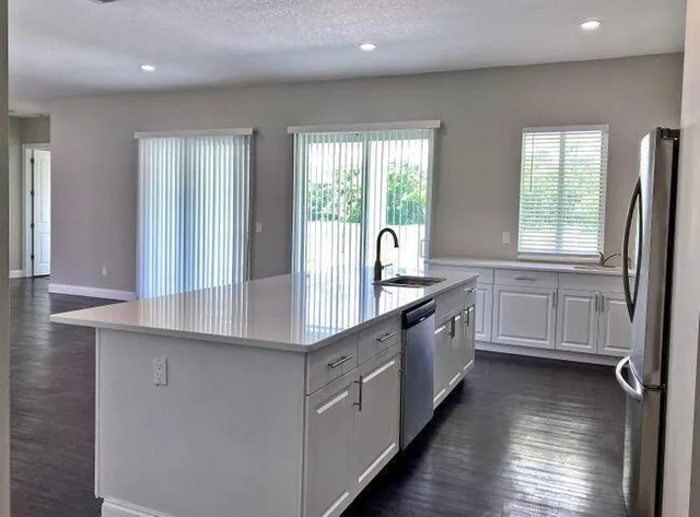 a large white kitchen with granite countertop a large window