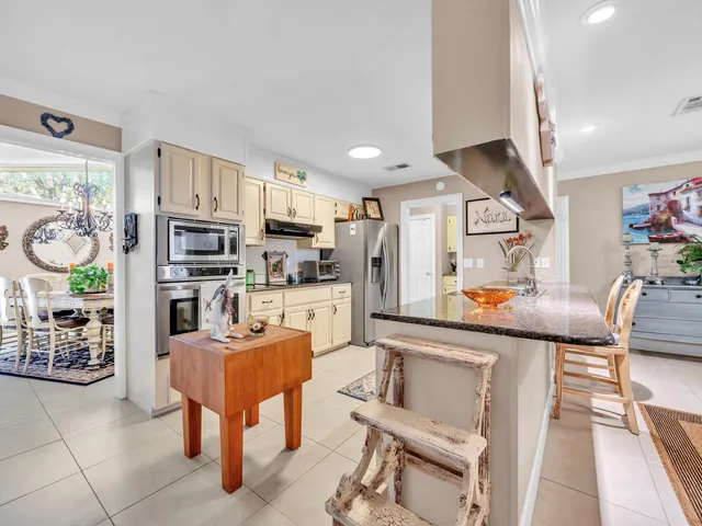 a living room with stainless steel appliances furniture and a kitchen view
