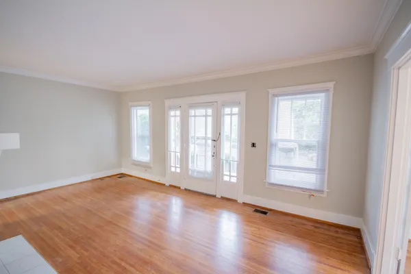 a view of an empty room with wooden floor and a window