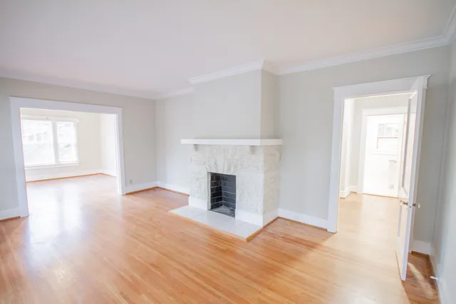 an empty room with wooden floor fireplace and windows