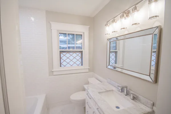 a bathroom with a sink vanity granite toilet and a mirror