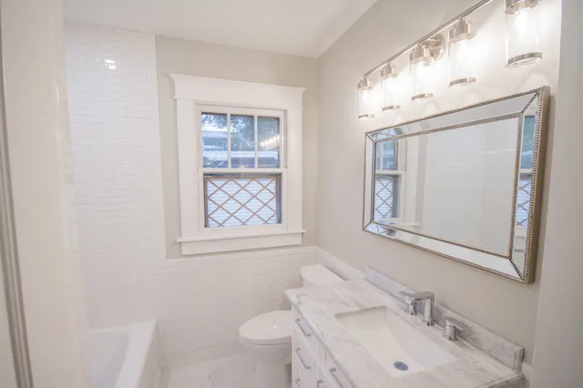 a bathroom with a sink vanity granite toilet and a mirror