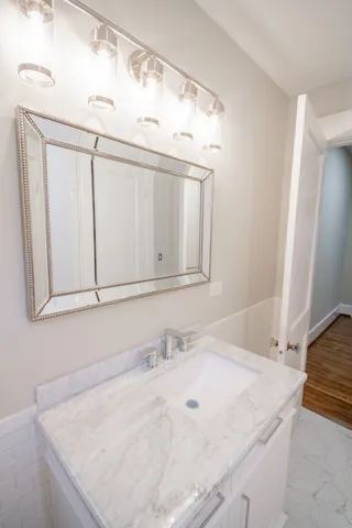 a bathroom with a granite countertop sink and white cabinets
