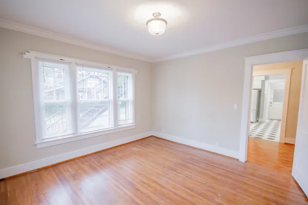 a view of empty room with wooden floor and fan