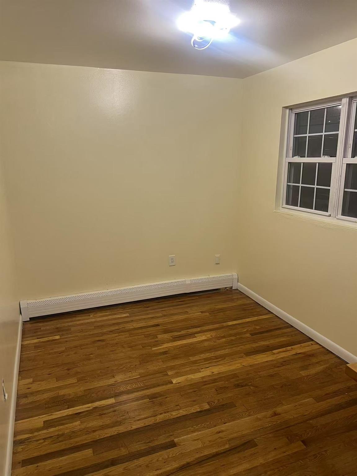 1460 Sutter Avenue, Unit 2 Brooklyn, NY 11208 - Photo 1 of 5 a view of an empty room with wooden floor and windows