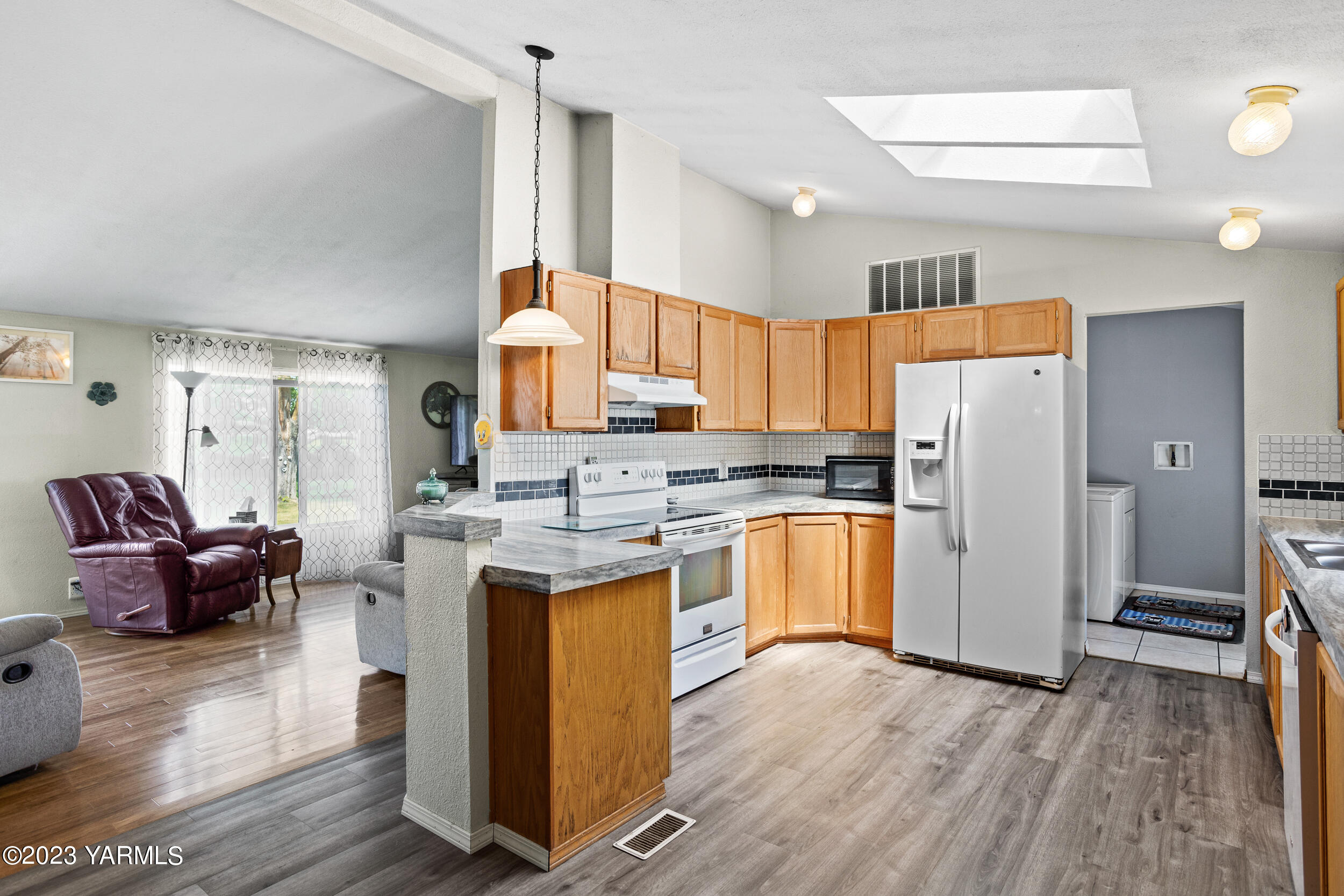 910 Robinson Road Grandview, WA 98930 - Photo 11 of 37 a kitchen with a refrigerator a sink dishwasher with a dining table and wooden floor