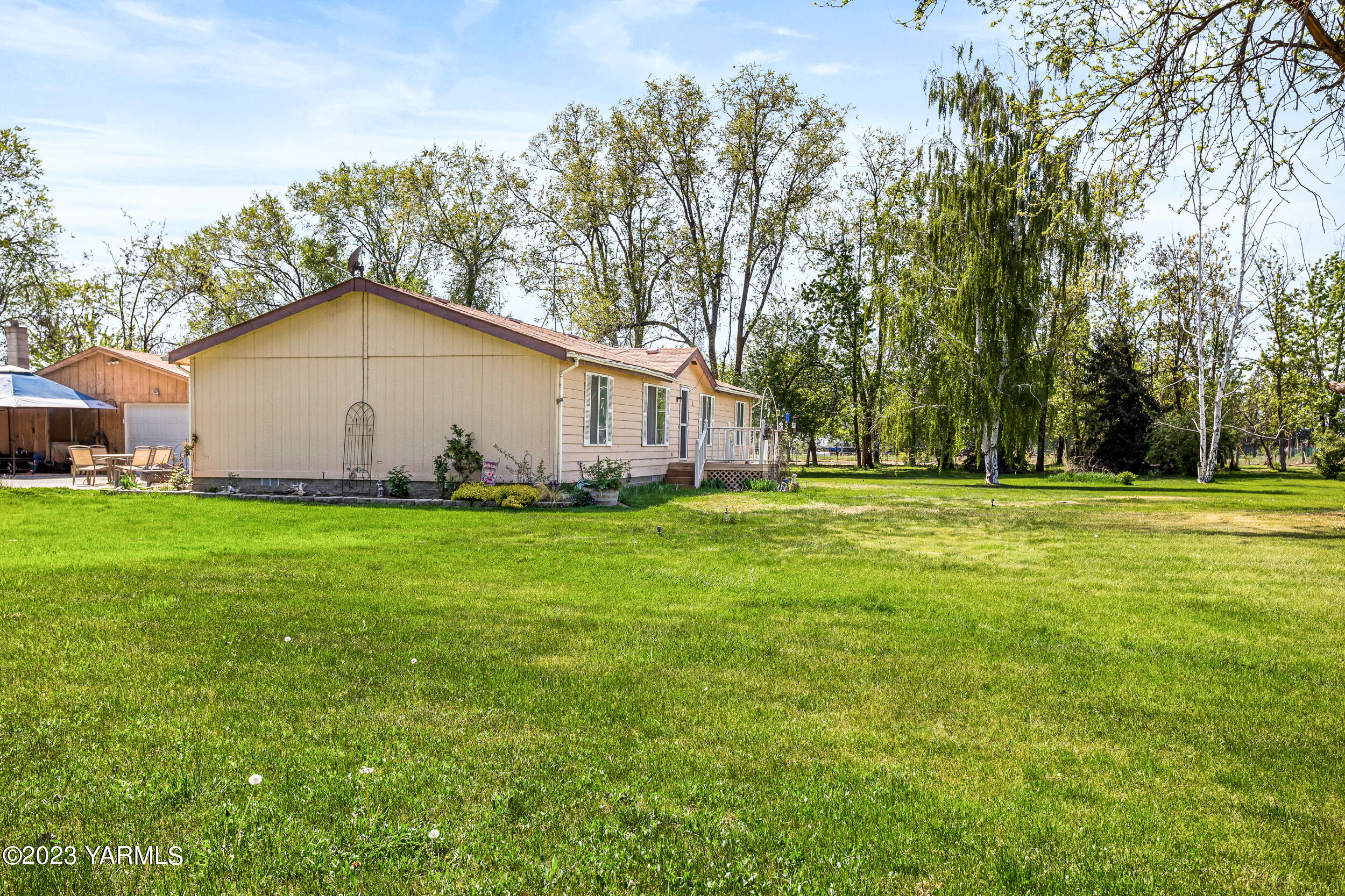 910 Robinson Road Grandview, WA 98930 - Photo 28 of 37 a white house with a big yard and large trees