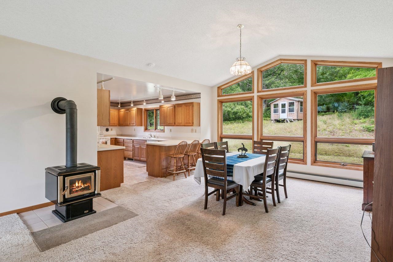75920 Ondossagon Road Washburn, WI 54891 - Photo 4 of 29 Dining area with a wood stove, vaulted ceiling, light colored carpet, a baseboard heating unit, and light tile patterned floors