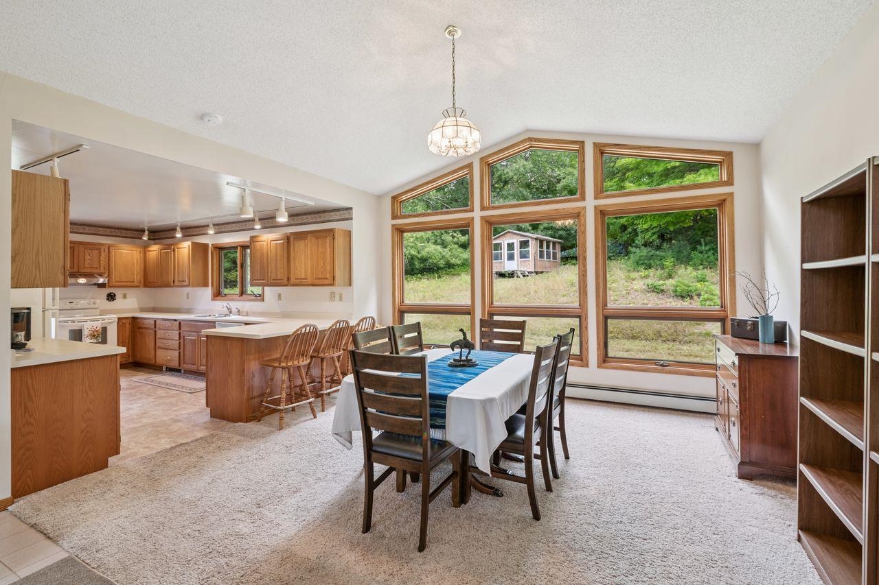 75920 Ondossagon Road Washburn, WI 54891 - Photo 6 of 29 Dining area featuring vaulted ceiling, a textured ceiling, a baseboard radiator, a chandelier, and light tile patterned floors