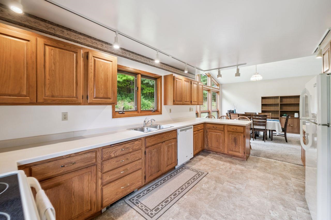 75920 Ondossagon Road Washburn, WI 54891 - Photo 7 of 29 Kitchen with track lighting, light countertops, brown cabinetry, white appliances, and a peninsula