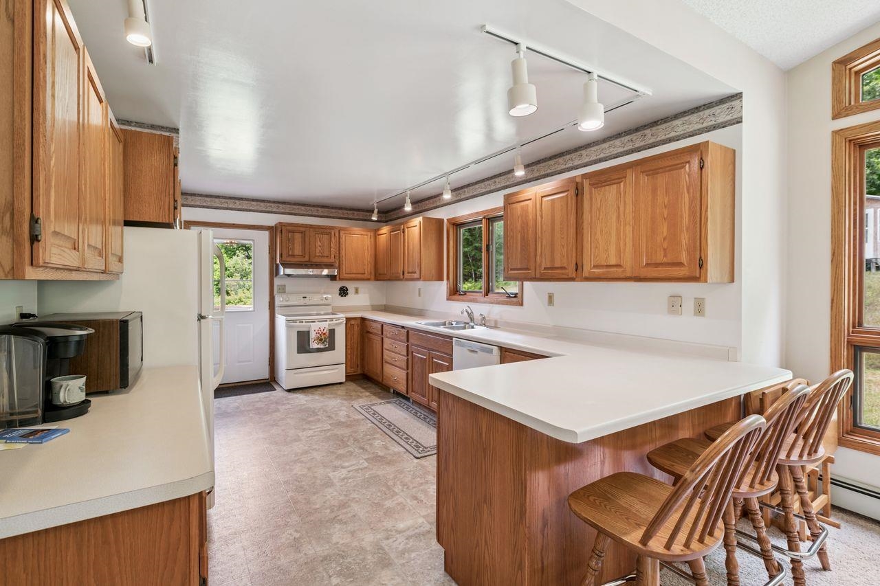 75920 Ondossagon Road Washburn, WI 54891 - Photo 8 of 29 Kitchen featuring rail lighting, a peninsula, white appliances, and light countertops