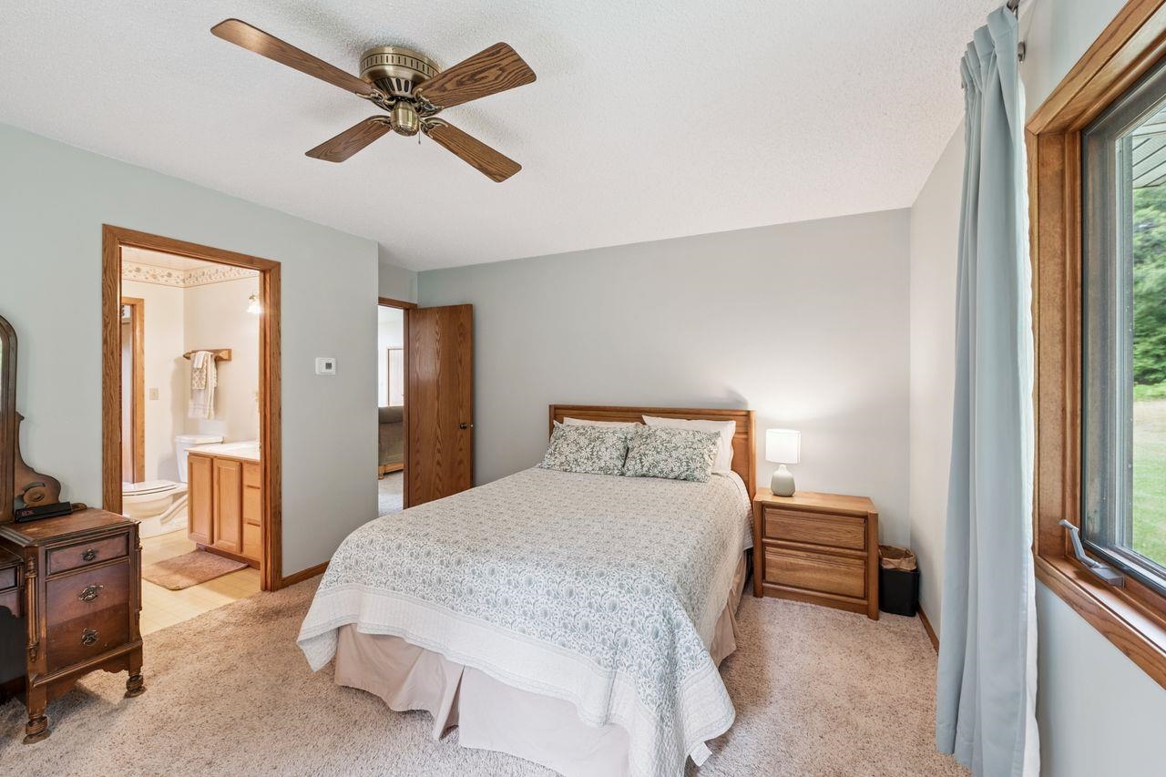 75920 Ondossagon Road Washburn, WI 54891 - Photo 10 of 29 Bedroom featuring light colored carpet, ceiling fan, and connected bathroom