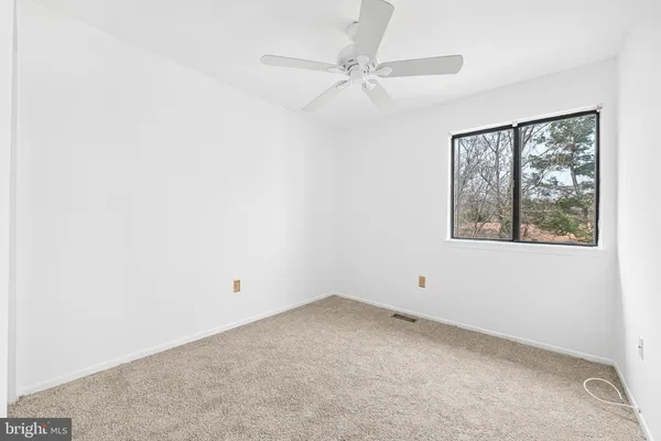 an empty room with a window and a fan