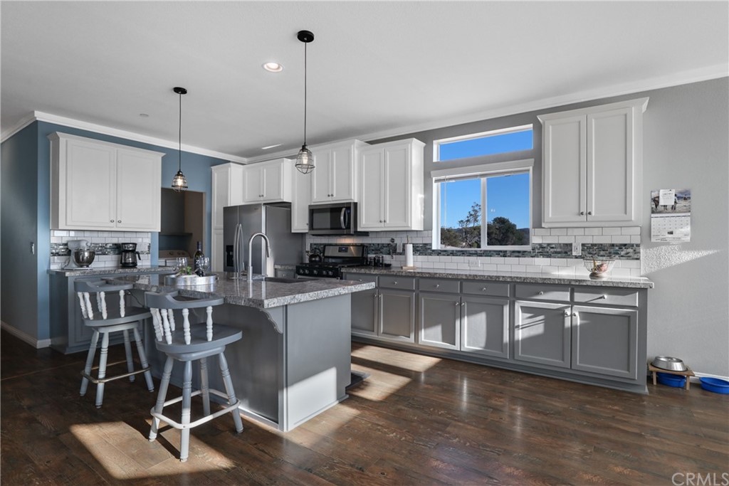 60600 Burnt Valley Road Anza, CA 92539 - Photo 9 of 46 a kitchen with stainless steel appliances granite countertop a stove a sink a refrigerator white cabinets and chairs with wooden floor