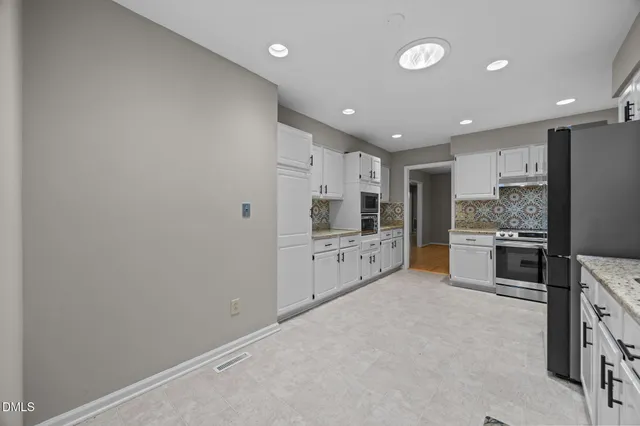 a large white kitchen with a white stove top oven and refrigerator