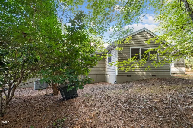 a backyard of a house with potted plants and a large tree