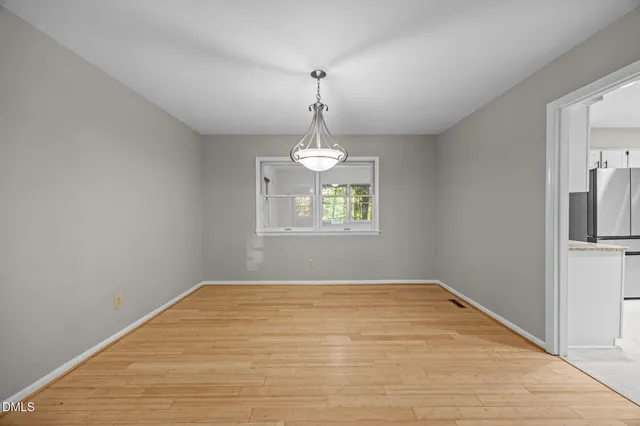 a view of an empty room with window and wooden floor