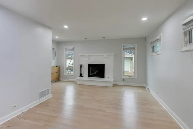 an empty room with wooden floor and fireplace