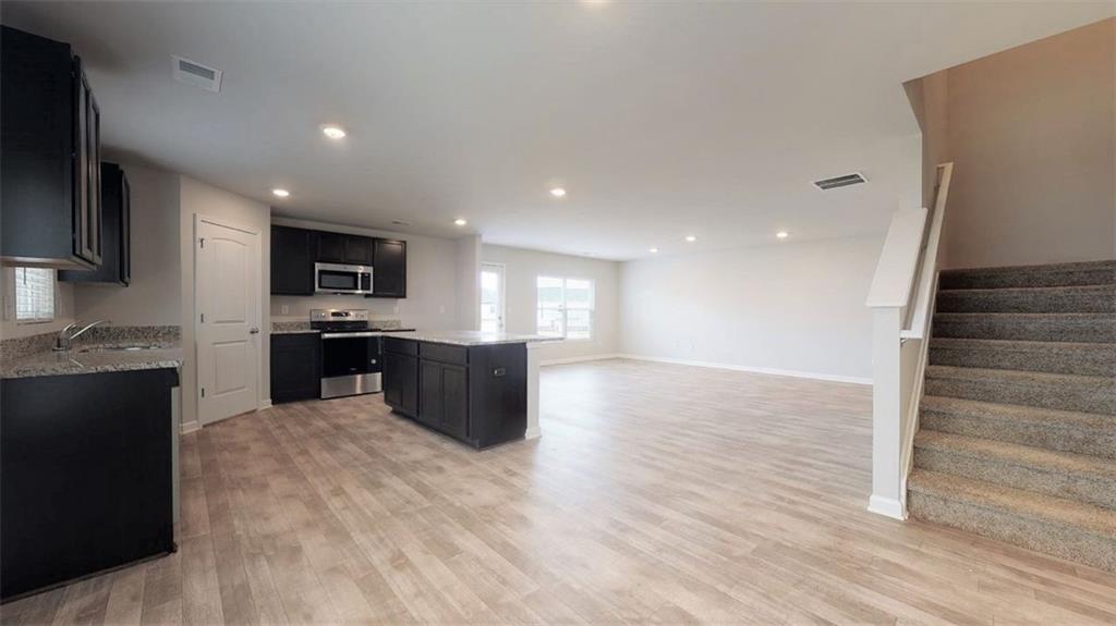121 Weldon Road McDonough, GA 30253 - Photo 13 of 32 a large kitchen with stainless steel appliances kitchen island granite countertop a stove top oven a sink and dishwasher with wooden floor