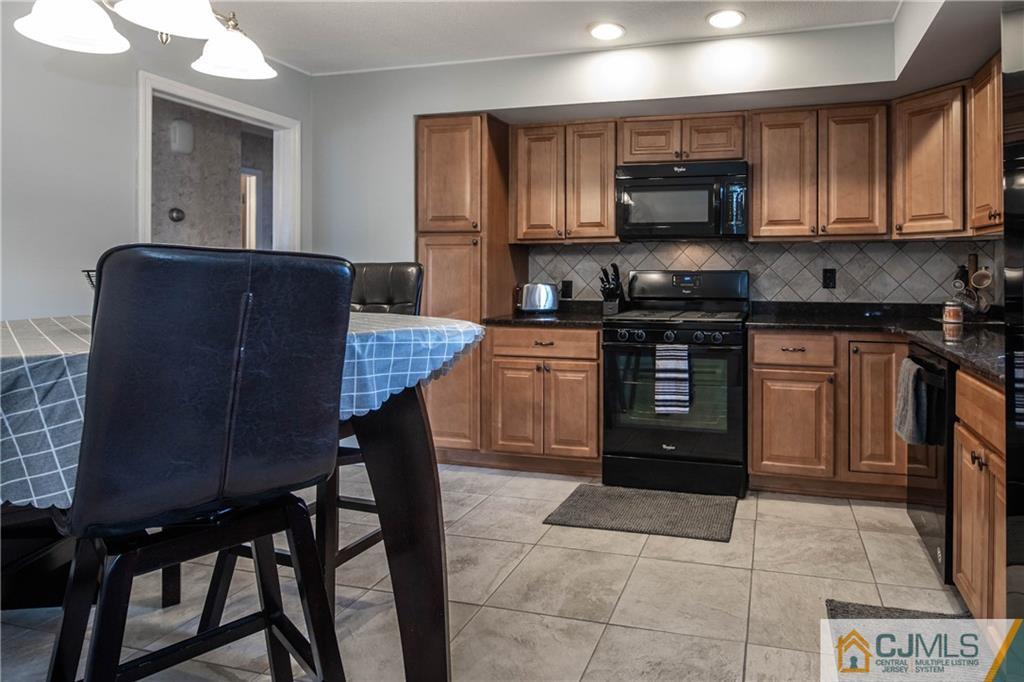 207 South Hill Road Colonia, NJ 07067 - Photo 5 of 47 a kitchen with stainless steel appliances granite countertop a stove top oven a sink a dining table and chairs