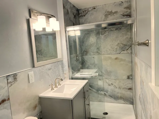 a bathroom with a sink mirror and shower