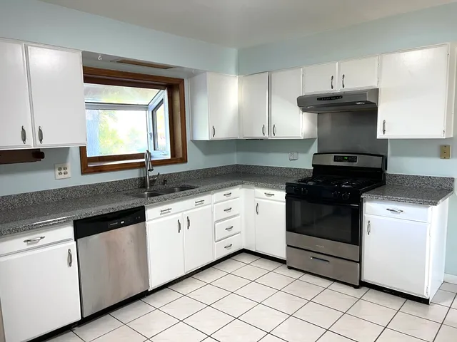 a kitchen with granite countertop white cabinets and white appliances