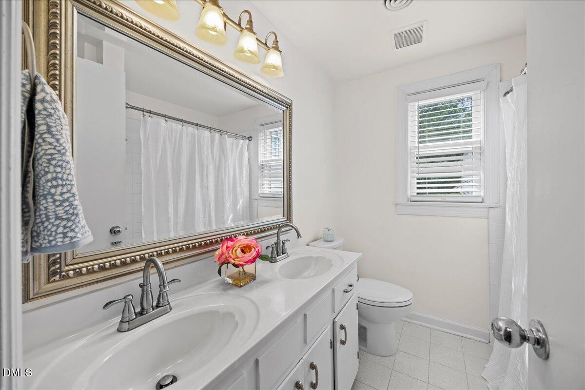 1627 Sutton Drive Raleigh, NC 27605 - Photo 19 of 33 a bathroom with a sink vanity granite toilet and a mirror