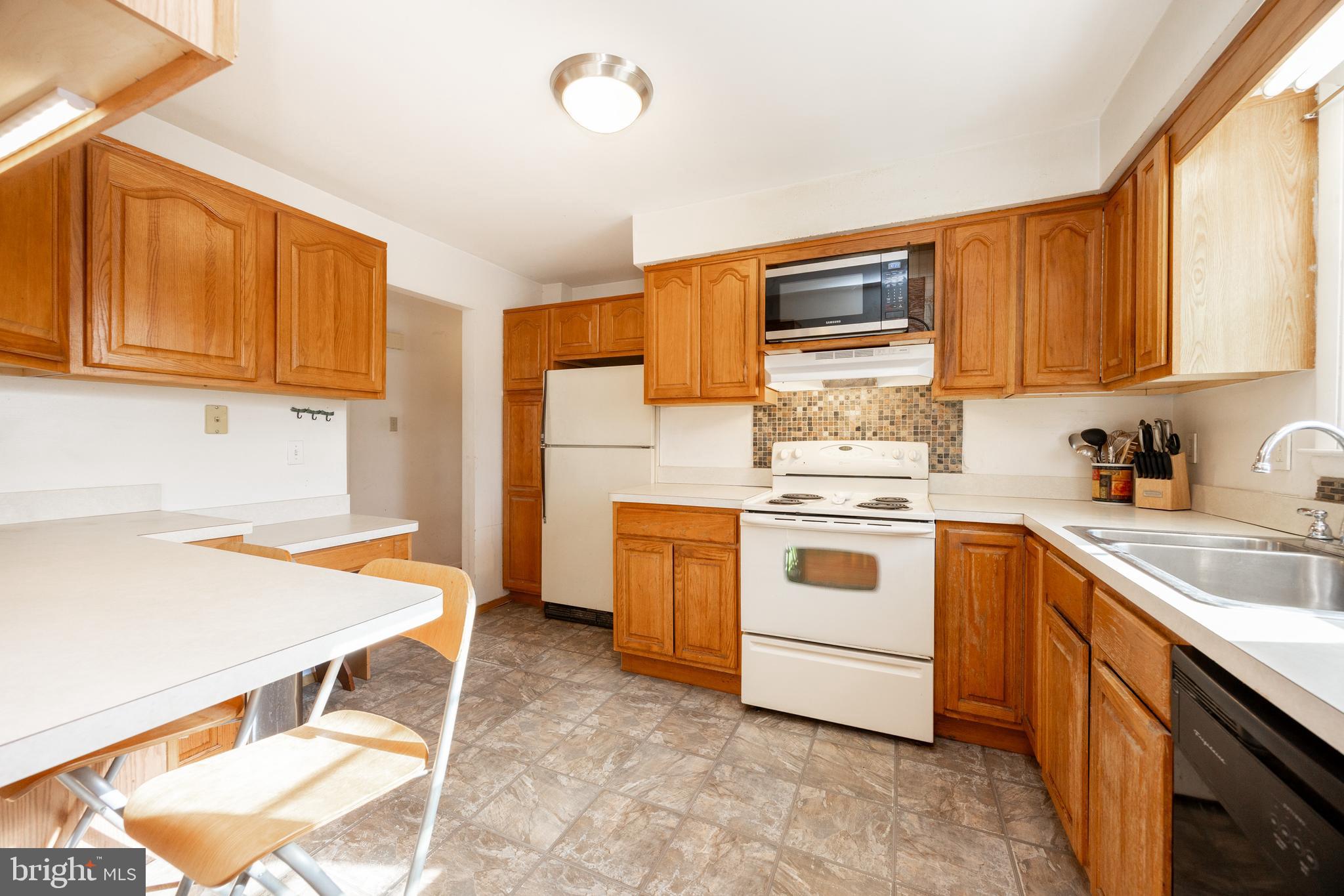 4455 Bethel Road Upper Chichester, PA 19061 - Photo 11 of 27 a white kitchen with stainless steel appliances granite countertop a stove and a sink