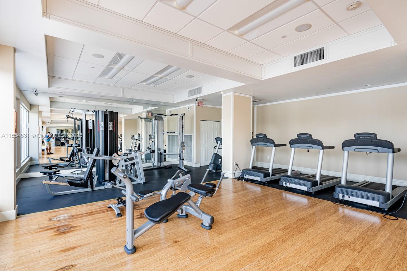 2801 Northeast 183rd Street, Unit 1401W Aventura, FL 33160 - Photo 5 of 26 a living room with gym equipment and a table