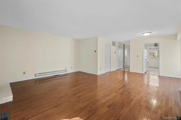 a view of an empty room with wooden floor and closet