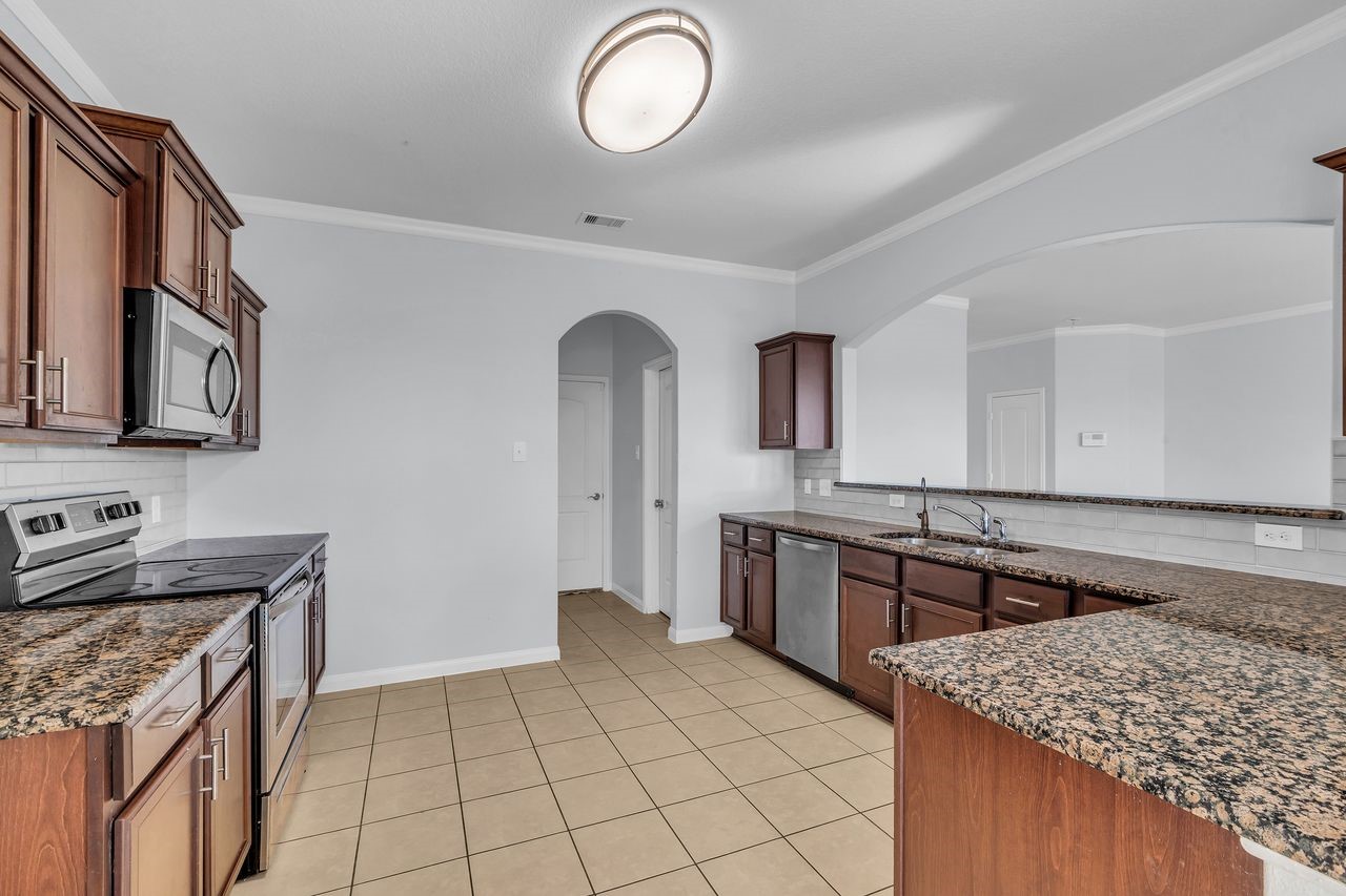 22703 Threefold Ridge Drive Hockley, TX 77447 - Photo 17 of 36 a kitchen with stainless steel appliances granite countertop a sink stove and cabinets
