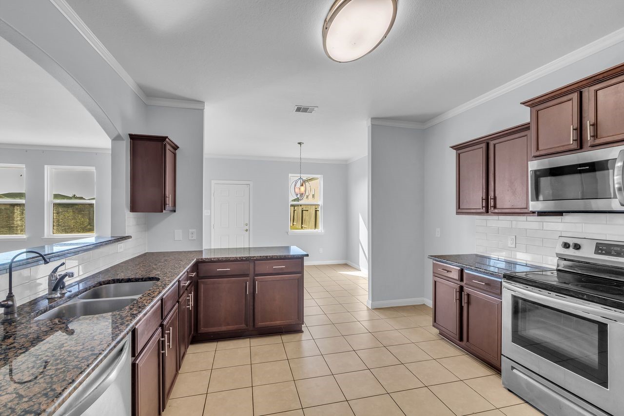 22703 Threefold Ridge Drive Hockley, TX 77447 - Photo 20 of 36 a kitchen with granite countertop a sink a stove top oven and cabinets
