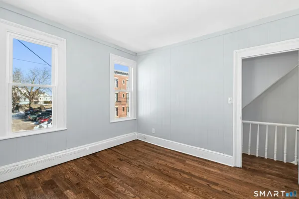 a view of an empty room with wooden floor and a window