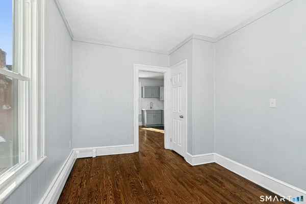 a view of an empty room with wooden floor and a window