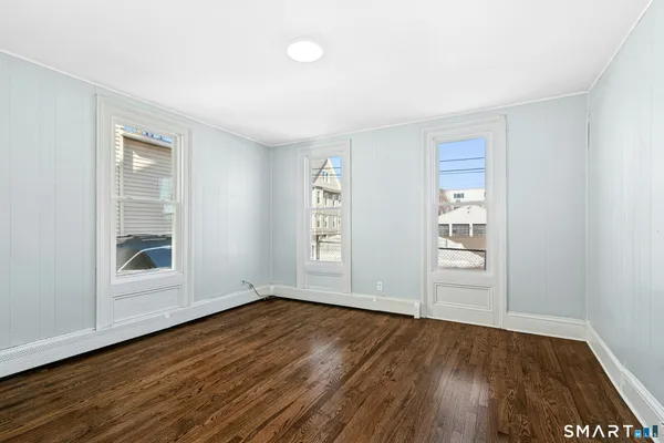 an empty room with wooden floor and windows