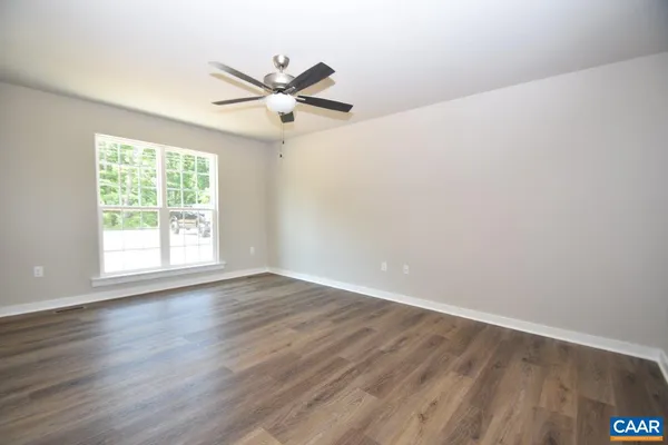 an empty room with wooden floor fan and windows
