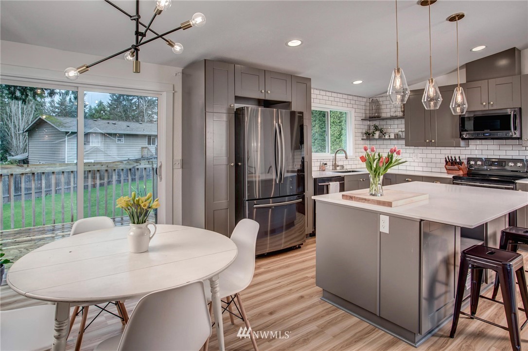 2321 177th Street Southeast Bothell, WA 98012 - Photo 10 of 28 a kitchen with stainless steel appliances granite countertop a stove refrigerator a dining table and chairs with wooden floor