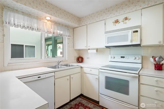 a kitchen with cabinets appliances a sink and a window