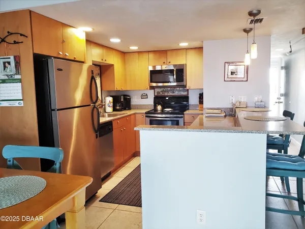 a kitchen with stainless steel appliances a refrigerator a sink a stove a microwave a dining table and chairs